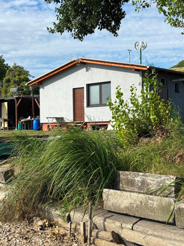 Detail der Hütte vom Ufer mit Gräsern im Vordergrund